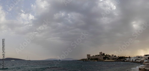 Wide angle panorama of Bodrum castle and beach on a cloudy and windy day.