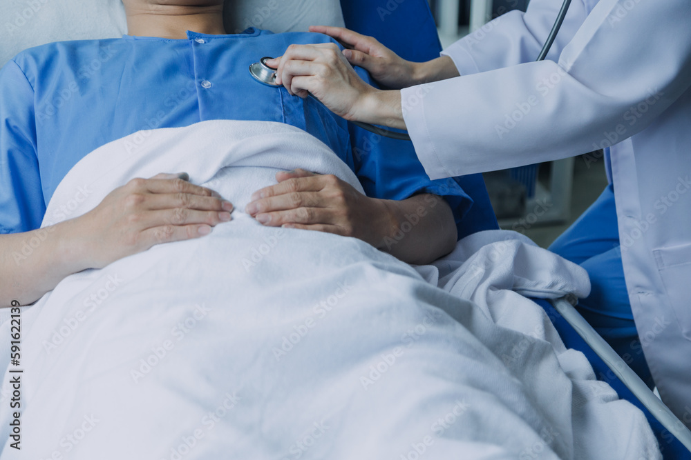 Side view of diverse doctors examining Asian female patient in bed in ward at hospital. Side view of diverse doctors examining Asian female patient in bed in ward at hospital.