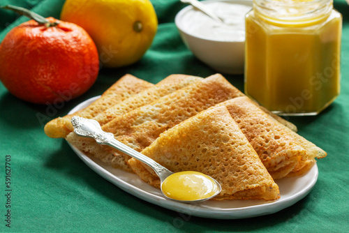 Pancakes served with fruit curd and sour cream, a traditional meal for Maslenitsa and Carnival.