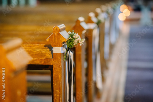 Foto Flowers added to the ends of chairs in the church