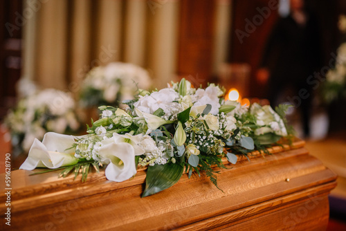 A coffin decorated with many flowers and candles in a beautiful church, ceremony photo