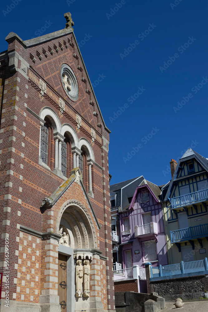 Exterior facade of the Romano-byzantine church of Saint Martin and other historic buildings in Mers-les-bains, in the Somme department of Northern France. Sunlit with blue sky. Copy space above right.