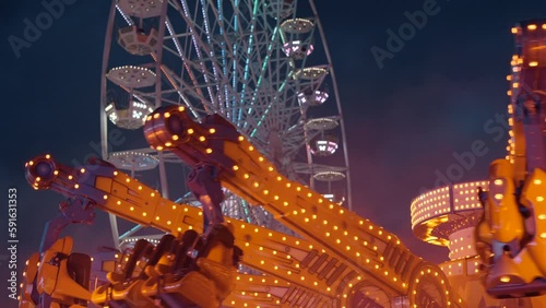 Ferris wheel. People having fun riding roller coaster at the amusement park at night