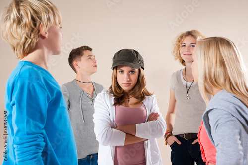 Portrait of Teenage Girl wearing Baseball Hat Looking at Camera, Standing in the Middle of Group of Teenage Boys and Girls, Studio Shot on White Background