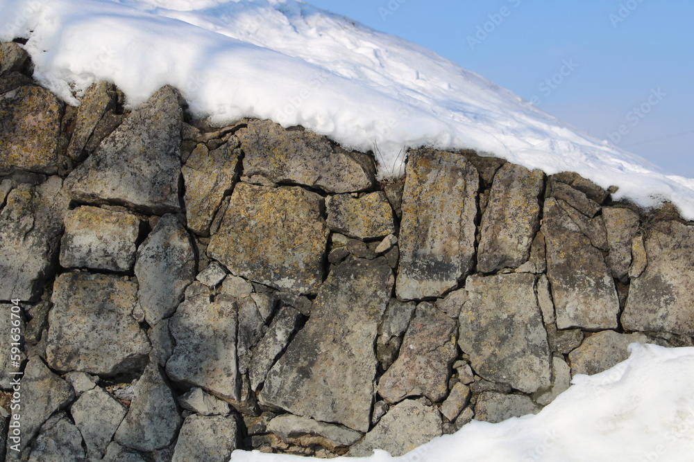 Old stone wall or rock covered by snow Old stone wall or rock covered by snow