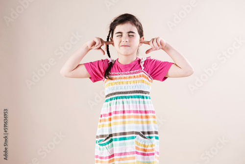 Portrait of Girl with Eyes Closed and Fingers in Ears in Studio