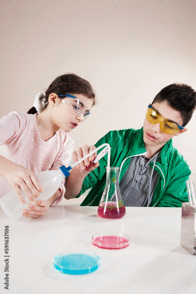 Boy and Girl wearing Safety Glasses Pouring Liquid into Beaker, Mannheim, Baden-Wurttemberg, Germany Boy and Girl wearing Safety Glasses Pouring Liquid into Beaker, Mannheim, Baden-Wurttemberg, Germany