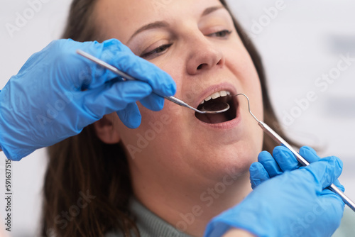 female patient undergoing dental care with a professional dentist using dental mirror and equipment in a state-of-the-art dental office. 