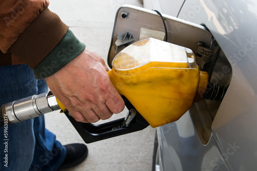 A man's hand is refueling the car with a yellow pump,close up taken © Gulsen