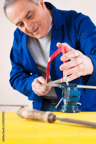Man Cutting a Pipe for a Plumbing Project, in Studio photo