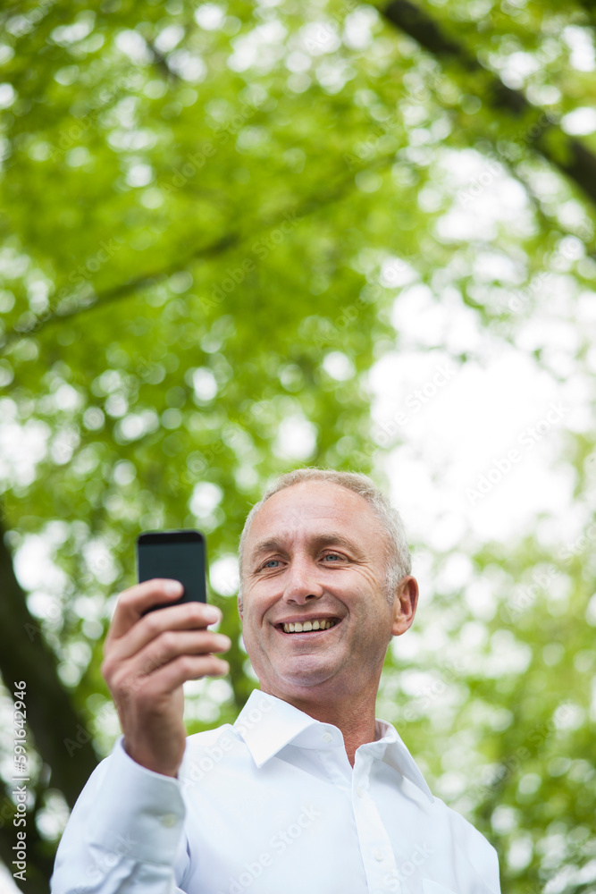 Close-up of mature man looking at smartphone in park, Mannheim, Germany Close-up of mature man looking at smartphone in park, Mannheim, Germany