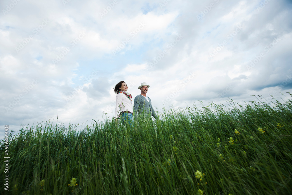 Mature couple walking in field of grass, Germany Mature couple walking in field of grass, Germany