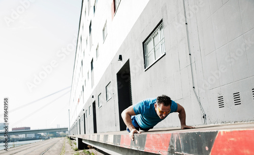 Mature man doing push-ups outdoors, on loading dock in front of warehouse, Mannheim, Germany photo