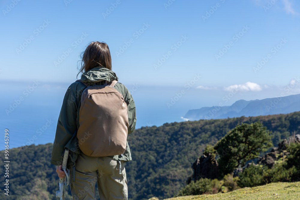Woman with a backpack taking in the majestic view of a coastal landscape