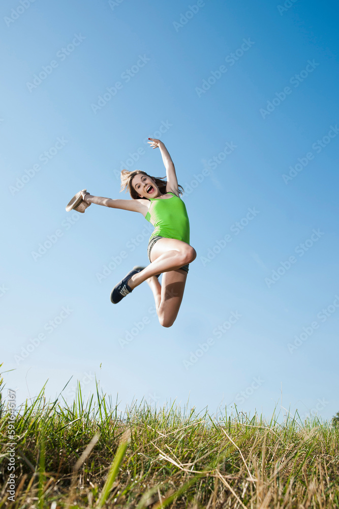 Teenaged girl jumping in mid-air over field, Germany Teenaged girl jumping in mid-air over field, Germany