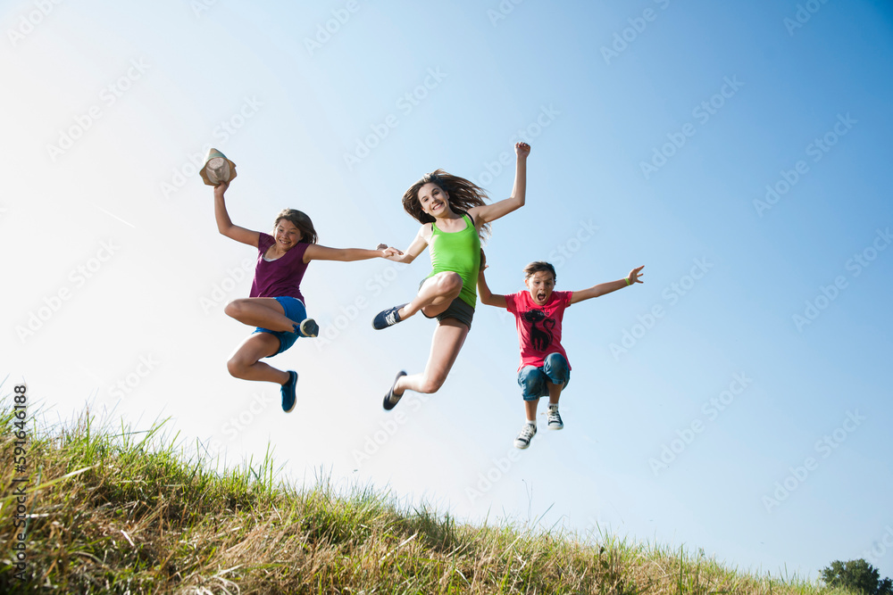 Girls jumping in mid-air over field, Germany Girls jumping in mid-air over field, Germany