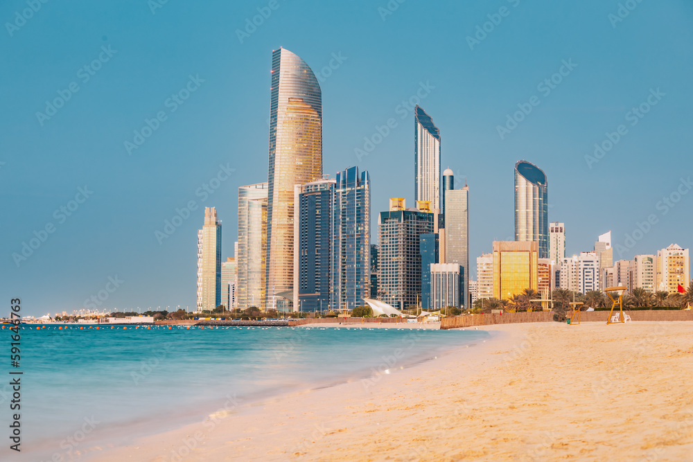 Panoramic view of stunning sandy beach near Corniche seaside embankment with great sunset view of Abu Dhabi, UAE towering skyscrapers
