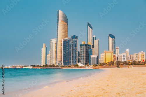 Obraz na płótnie Panoramic view of stunning sandy beach near Corniche seaside embankment with great sunset view of Abu Dhabi, UAE towering skyscrapers w salonie