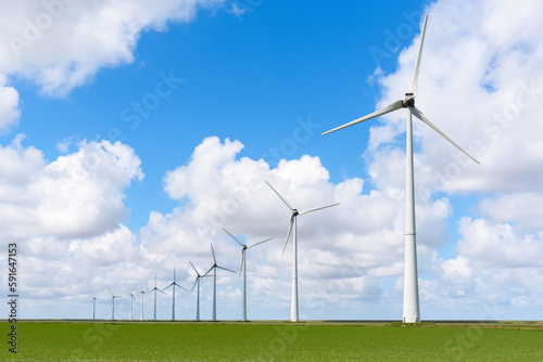 Row of wind turbines in the countryside under blue sky with clouds in summer