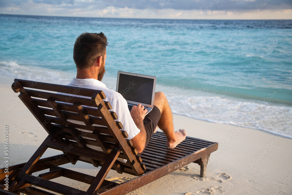 man working on laptop on tropical beach man working on laptop on tropical beach