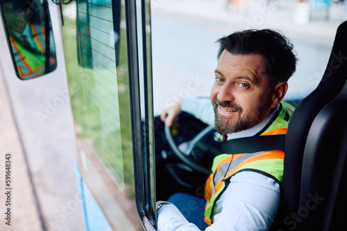 Happy bus driver in vehicle cabin looking at camera.