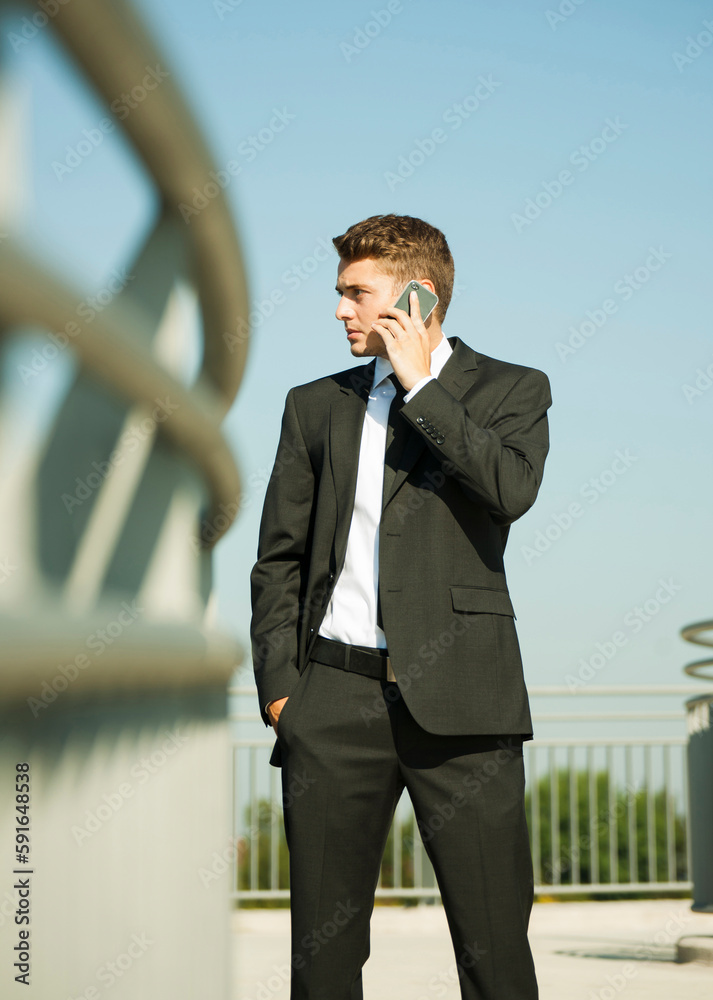 Portrait of businessman standing by railing and using cell phone, Germany Portrait of businessman standing by railing and using cell phone, Germany