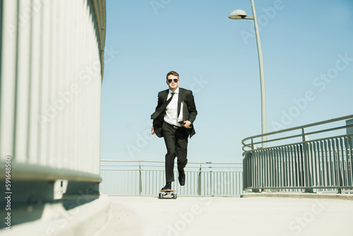 Businessman skateboarding on walkway holding binder, Germany photo