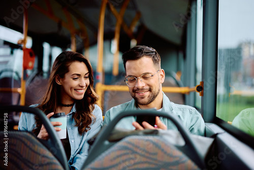 Happy couple using mobile phone while riding in bus.
