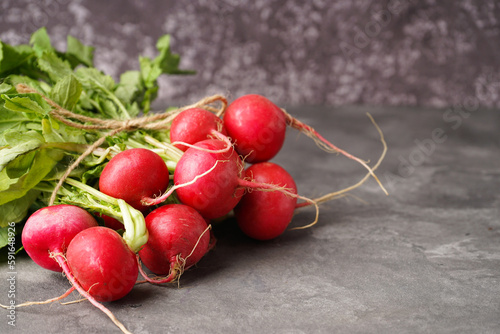Red radishes bunch on a grey background, space for text. Close-up.