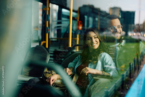 Young happy couple looking through window while riding in bus. photo