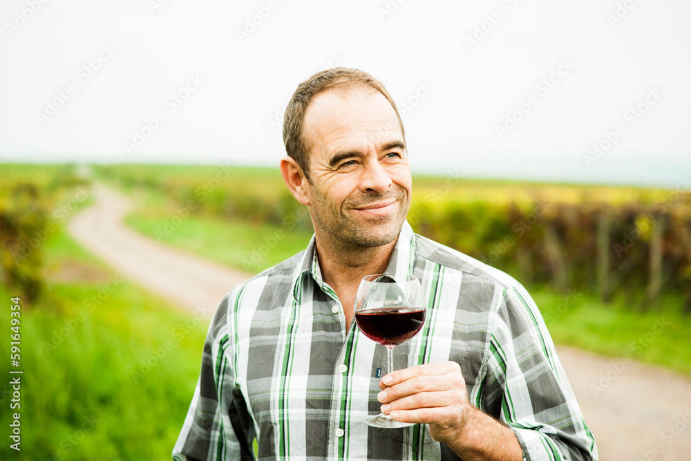 Portrait of vintner standing in vineyard, holding glass of wine, Rhineland-Palatinate, Germany Portrait of vintner standing in vineyard, holding glass of wine, Rhineland-Palatinate, Germany