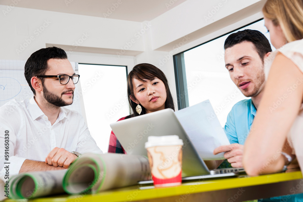 Close-up of group of young business people sitting around table, meeting and in discussion, Germany