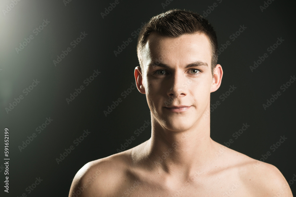 Close-up portrait of young man looking at camera, studio shot on black background
