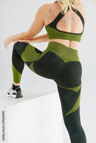 rear view. a women in a tracksuit posing with a white cube