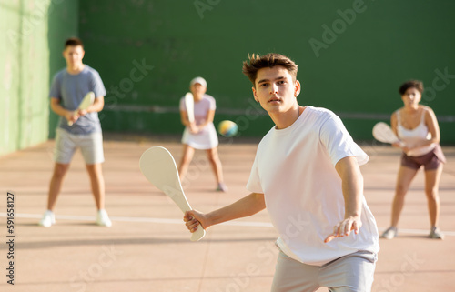 Bild auf Leinwand Concentrated young man paleta fronton player hitting ball with a racket