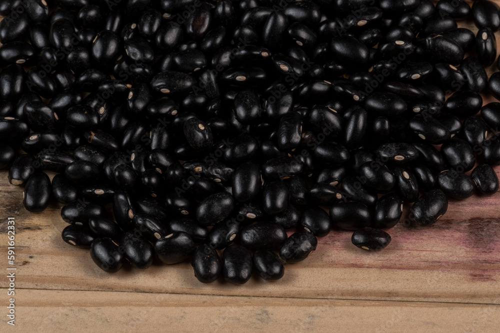 heap of black beans scattered over rustic wood heap of black beans scattered over rustic wood