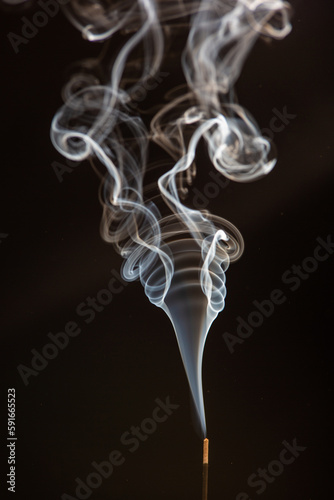 white smoke in interesting vortex pattern on black background. illustration for smoking, air pollution and fire