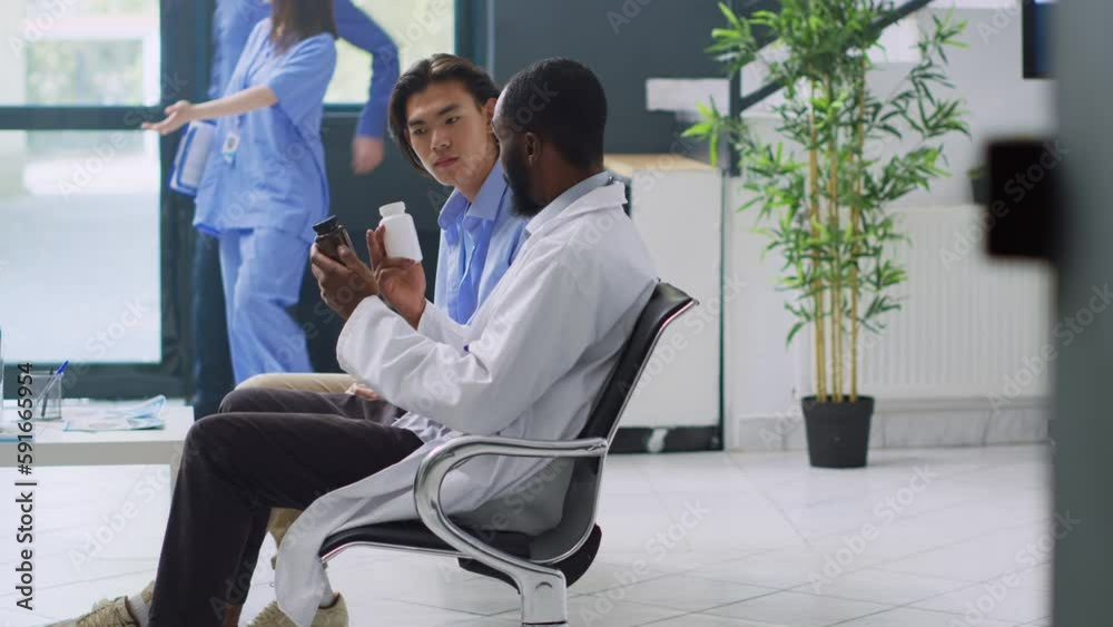 Doctor discussing medication treatment with patient, showing supplements and vitamins bottle. Asian man having medical checkup visit consultation in hospital reception. Medicine concept Doctor discussing medication treatment with patient, showing supplements and vitamins bottle. Asian man having medical checkup visit consultation in hospital reception. Medicine concept