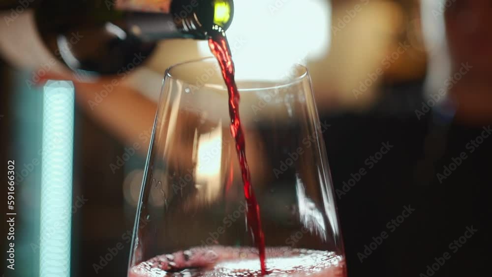 bartender pouring red luxury wine in wineglass, closeup macro