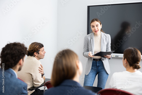Young female professor explaining subject to classroom full of students photo