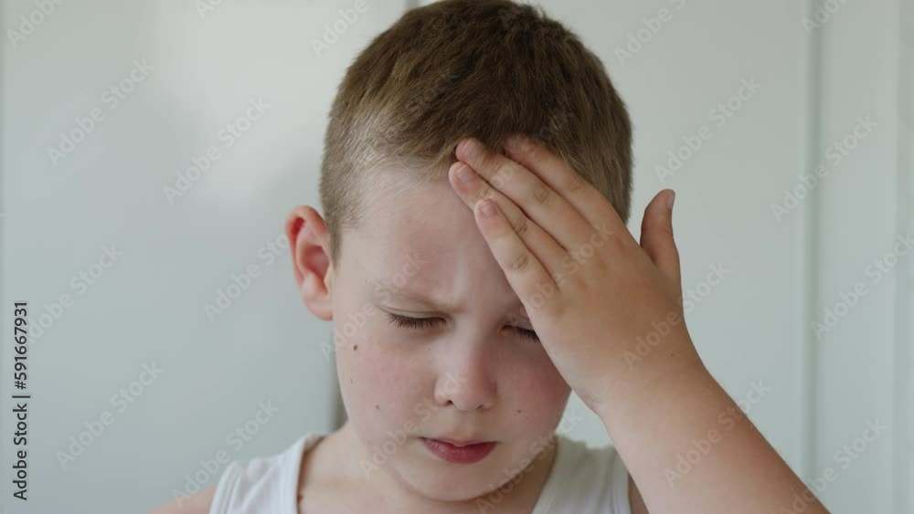 Portrait of european white boy scratching forehead with hand, closeup