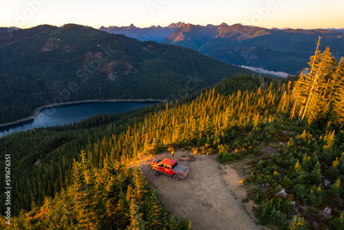 Drone shot of a pickup truck in front of volcanic mountain. Mount Rainier in the background. A perfect spot for camping off the grid.