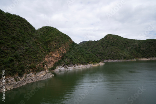 View of the lake, steep rocky hills and forest in a summer day. 