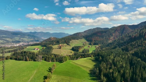 ALPS, AUSTRIA - OCTOBER, 2022: Aerial view of austrian mountain village Lendorf and beautiful valley. Green meadows and autumn forest with yellow leaves around. photo