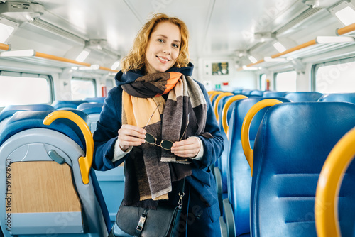 Young woman passenger smiling and enjoying on her journey by train in Europe and looking at camera. Train turism concept. 