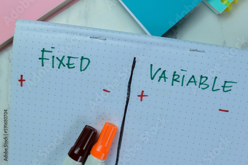 Concept of Fixed and Variable write on book isolated on Wooden Table.