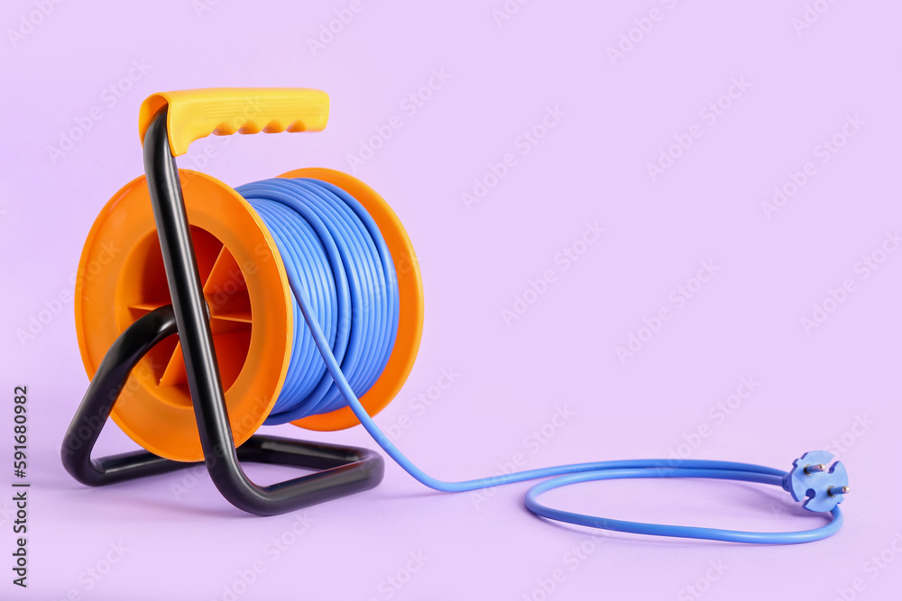 Extension electric cable reel on lilac background Extension electric cable reel on lilac background