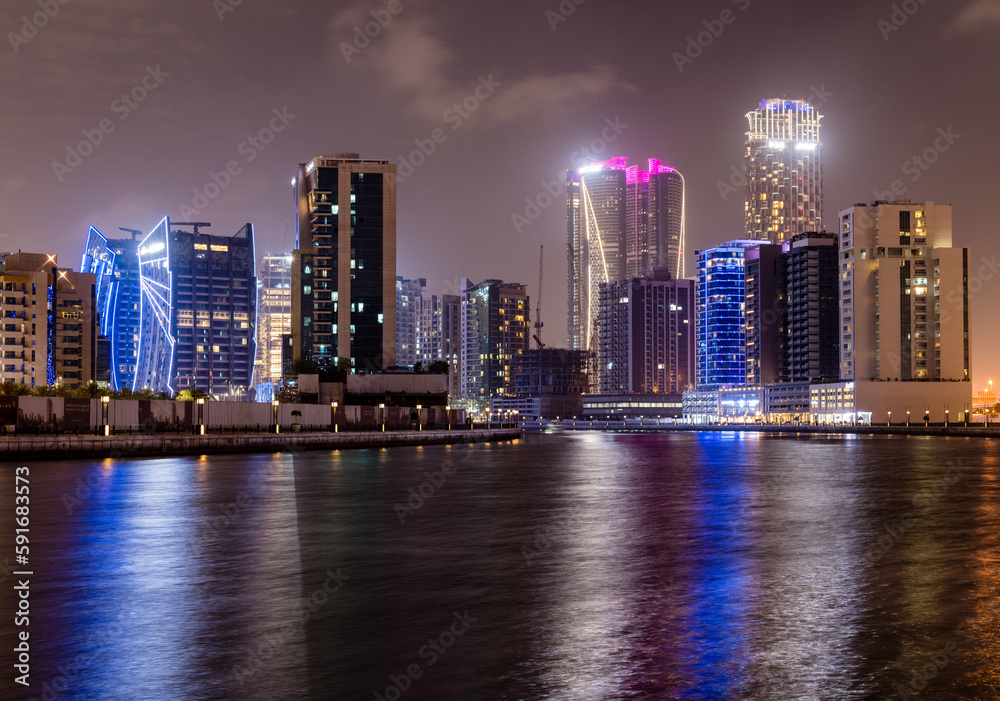 Fototapeta premium Night view of skyline of apartments buildings alongside canal in Business Bay