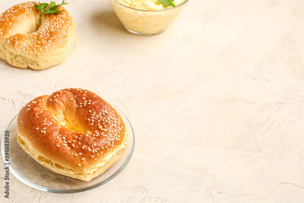 Plate with tasty bagels on light background