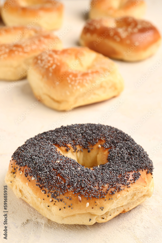 Tasty bagels with poppy seeds on light background